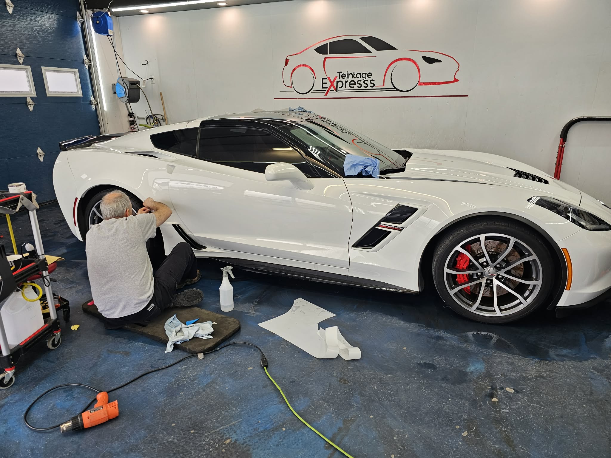 Corvette blanche en atelier comme exemple de travail en cours sur des vitres teintees